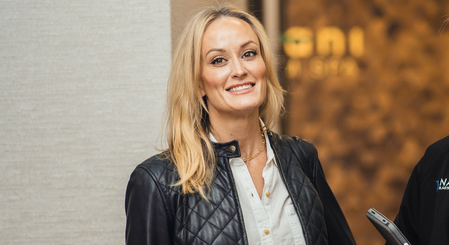 Smiling woman in casual black leather jacket.