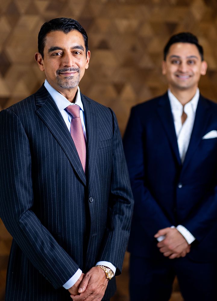 Two men in formal suits posing confidently.