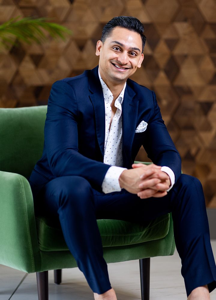Man smiling while sitting in a green chair.