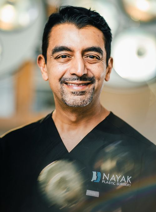 Dr. Nayak in surgical attire at clinic.