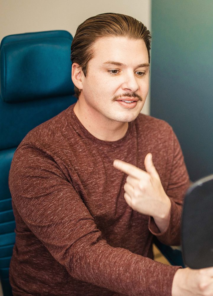 Man interacting with a mirror while seated.