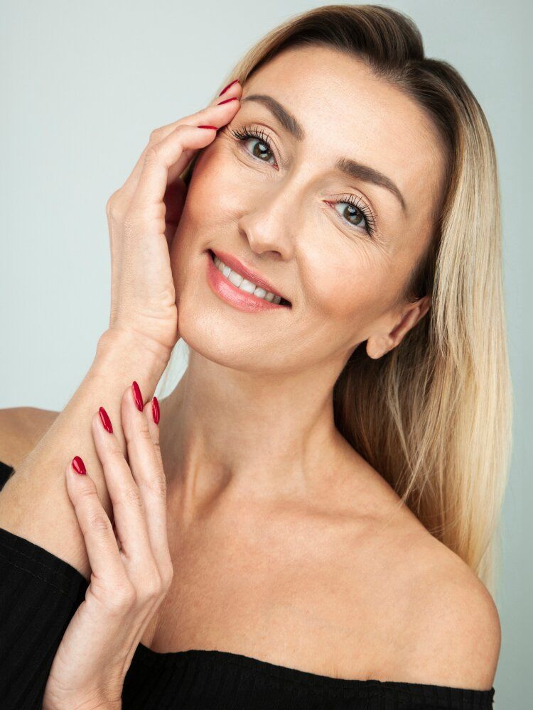 Smiling woman with long hair and red nails.