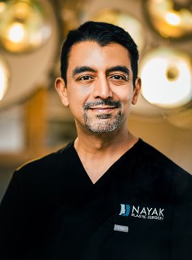 St. Louis facial plastic surgeon, Dr. Nayak in scrubs smiling confidently
